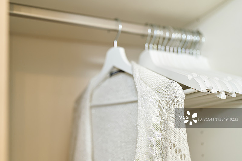 近距离的室内壁橱与衣服挂在货架在商店白色毛衣图片素材