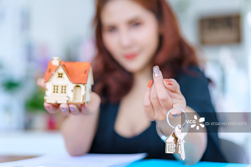 女房地产经纪人在签订租赁或购买合同后给新业主一把房子钥匙。图片素材
