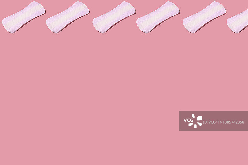 白色的衬垫图案在顶部，在粉红色的背景上。月经、排卵、生殖、疼痛、个人卫生的概念。图片素材