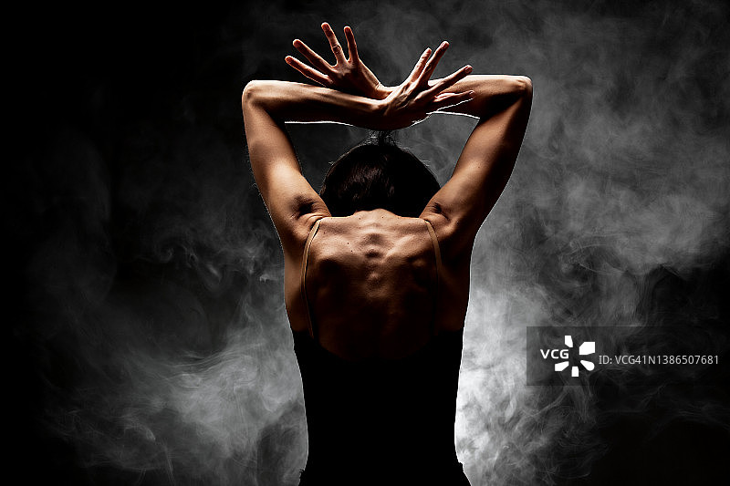 半剪影现代芭蕾舞演员摆姿势在黑暗的背景与烟雾图片素材