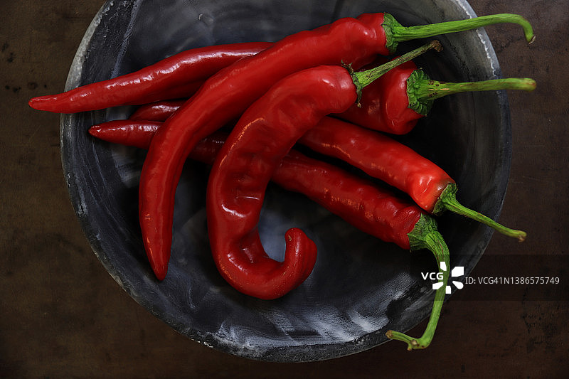 近距离的红辣椒在一个碗在黑暗的风化背景图片素材