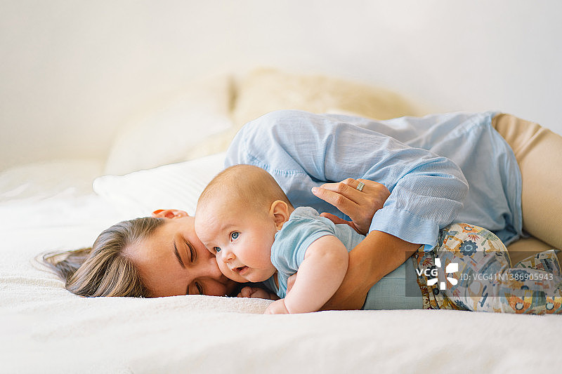一位年轻的母亲正在和一个小男孩玩。哺乳期婴儿的母亲图片素材
