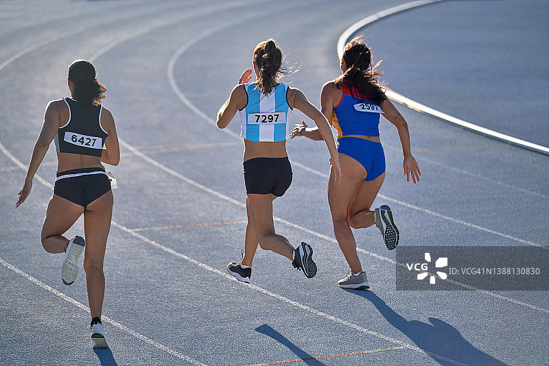 在蓝色跑道上比赛的女田径运动员图片素材