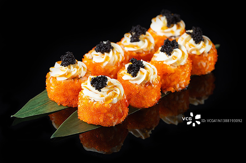 传统美味新鲜的寿司卷设置在黑色背景与反射。寿司卷配米饭，海苔，奶油芝士，鱼子酱，鳄梨。寿司菜单。日本厨房。亚洲食物图片素材