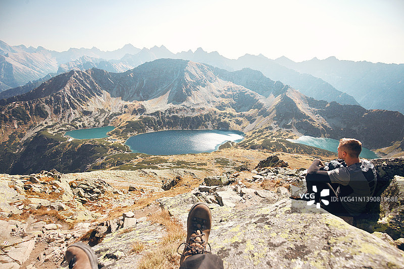 两个人坐在岩石山顶上，看着山上的湖泊图片素材