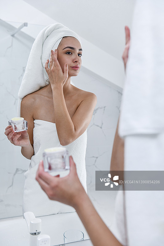 女性美容师在淋浴后尝试新的面部护肤霜图片素材
