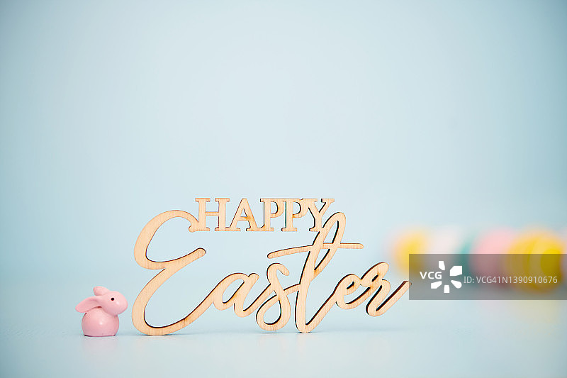 小小的粉色复活节兔子，蓝色背景，上面写着复活节快乐图片素材