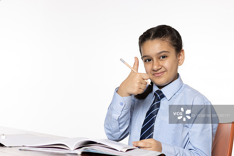 小学的小女孩坐在教室里学习，白色背景上竖起大拇指图片素材