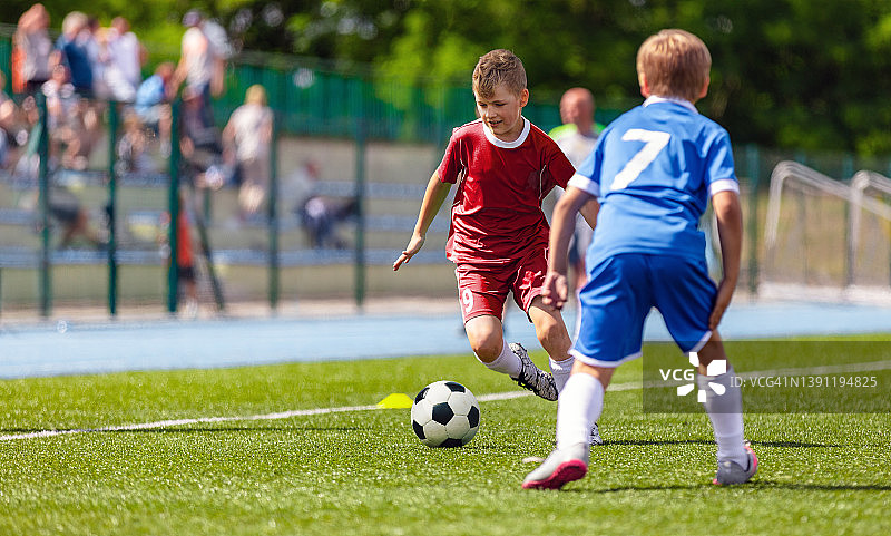 十几岁的男孩在比赛期间与足球赛跑。校队之间的欧洲足球比赛。运动的孩子在踢球图片素材