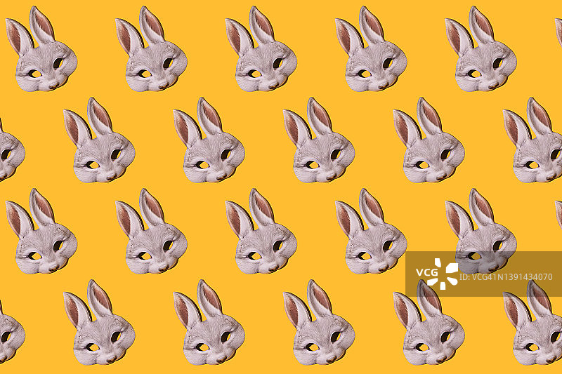 野兔兔面具图案与黄色背景上的硬阴影。伪装、化装、狂欢、复活节、趣味概念。图片素材
