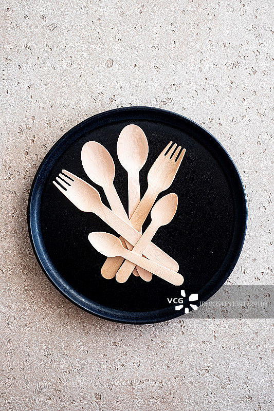一组木汤匙，叉子和茶匙在一个黑色的盘子或托盘上的混凝土背景，俯视图。“零浪费”的概念。副本的空间。图片素材