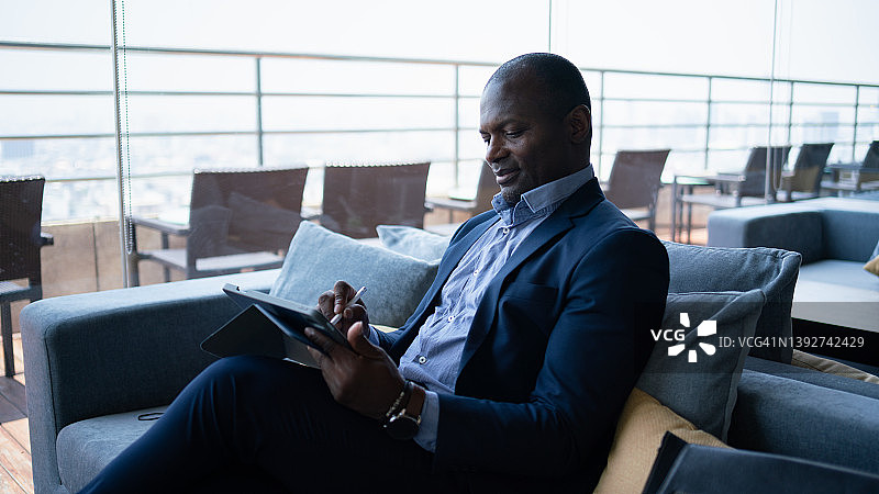商务人士坐在酒店或机场的休息室里使用智能手机。图片素材