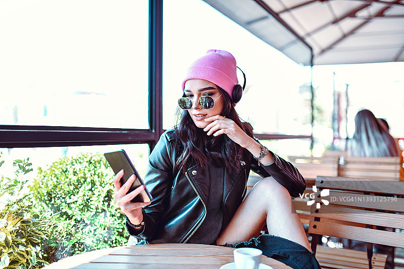 美女一边喝咖啡一边用智能手机听音乐图片素材