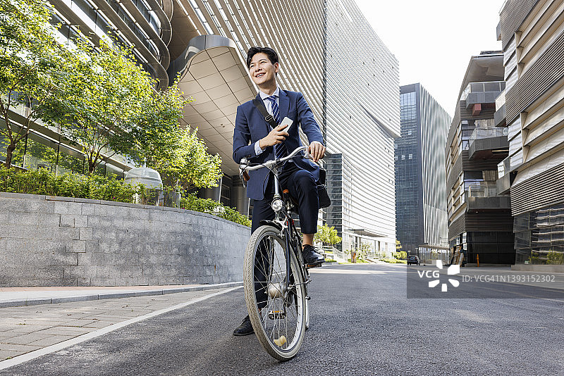 年轻开朗的商人骑着自行车去上班图片素材