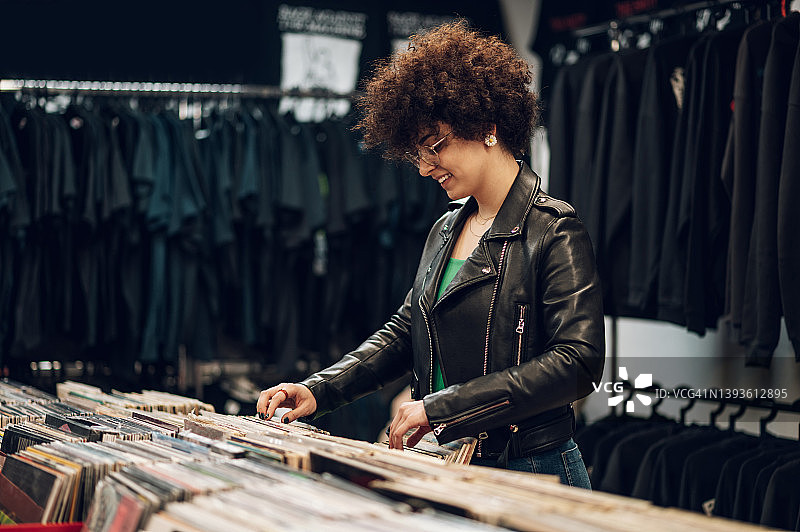 一个留着黑人发型的女人在唱片店里浏览黑胶唱片图片素材