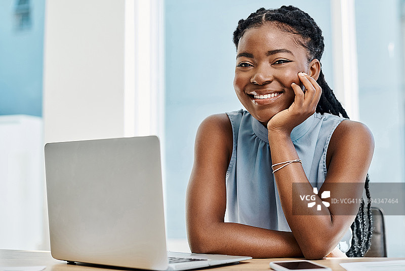 快乐的年轻黑人女商人独自在办公室里用笔记本电脑工作图片素材