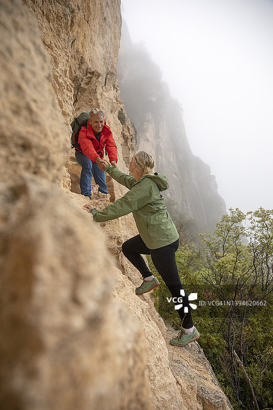 成年夫妇在雾中爬上岩壁图片素材