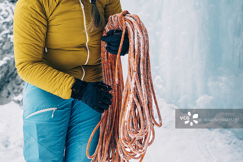 一名妇女在寒冷的山区环境中缠绕着一根登山绳图片素材