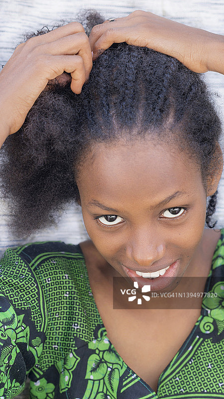 一位自然美人的肖像坐在她的房子前，编辫子，18岁，微笑的少女，自然的非洲式发型图片素材