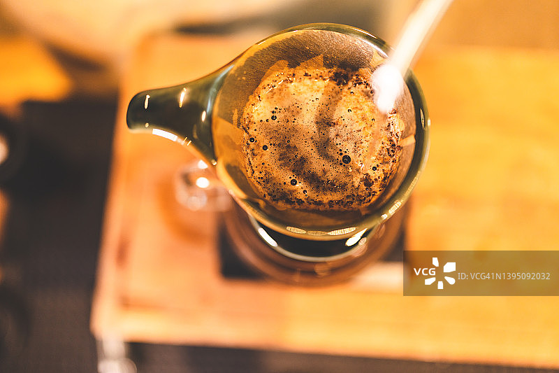 复古慢吧咖啡采用滴滤式咖啡滤器的概念，咖啡师制作热饮，饮料过程中冲泡的热水和阿拉比卡咖啡豆粉倒入杯中，具有香气和咖啡因的味道图片素材