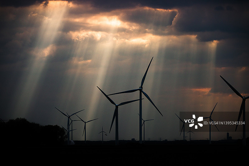 荷兰，黄昏时分，阳光透过云层照耀着风力涡轮机图片素材