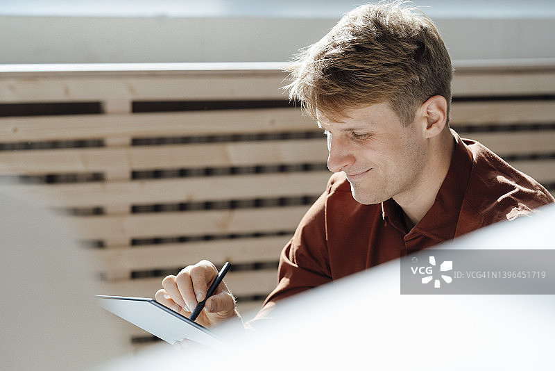 微笑的商人用数字化笔在办公室使用平板电脑图片素材
