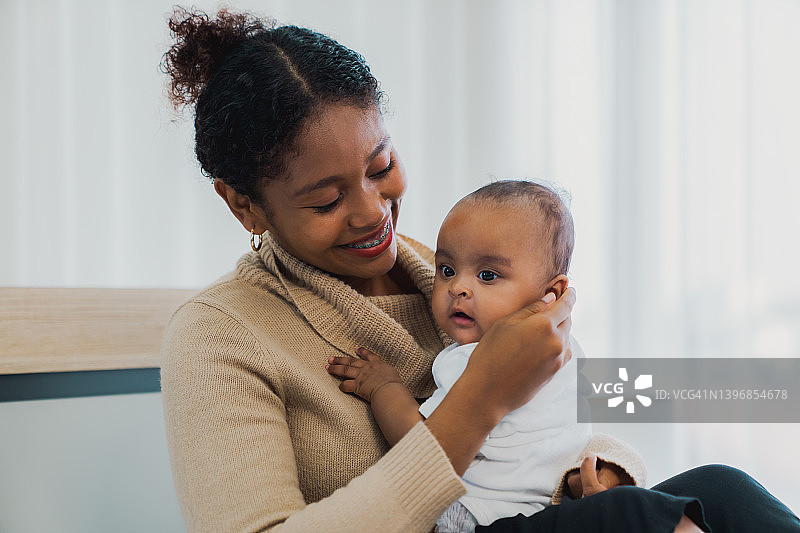肖像享受幸福的爱的家庭非洲裔美国人母亲玩可爱的小非洲裔美国婴儿。图片素材