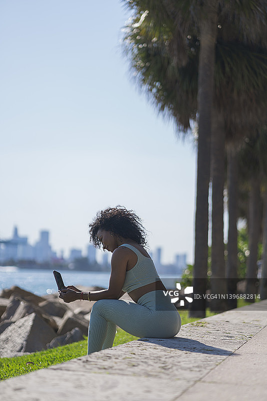 一名非洲裔拉丁妇女在海滩度假，同时用手机工作图片素材