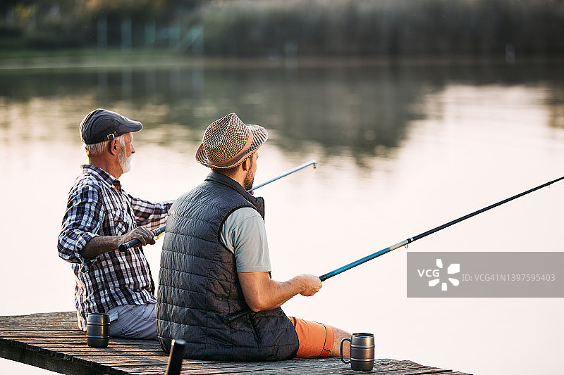 老人和他儿子在码头钓鱼的背影。图片素材