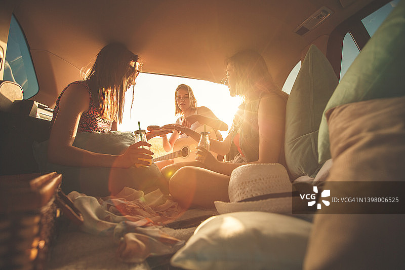 在汽车后备箱露营的闺蜜们玩得很开心
在日落图片素材