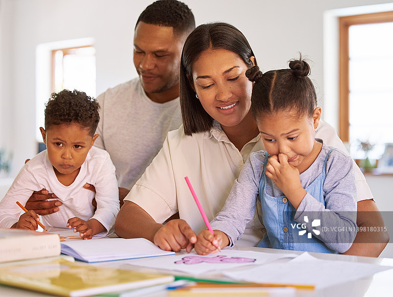 男孩和女孩通过父母的家庭教育学习。一对混血夫妇帮助他们的两个孩子涂色，做家庭作业和作业。家长在封锁期间教孩子图片素材