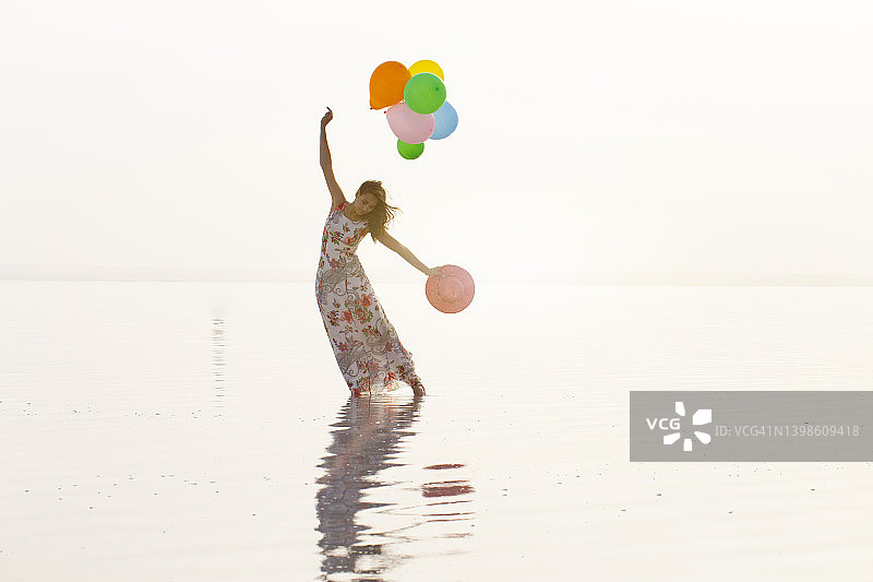 年轻女子举着气球穿过大海图片素材