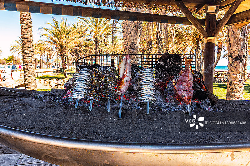 沙丁鱼，鱿鱼和其他鱼在驳船上烤，马拉加，西班牙。图片素材
