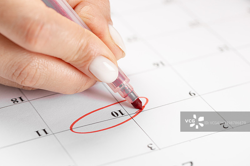 女性用红笔在日历上圈出日期、截止日期的概念图片素材
