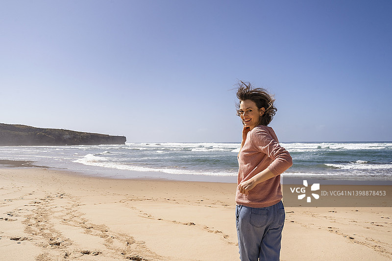 阳光明媚的日子里，快乐的女人在海滩上奔向大海图片素材