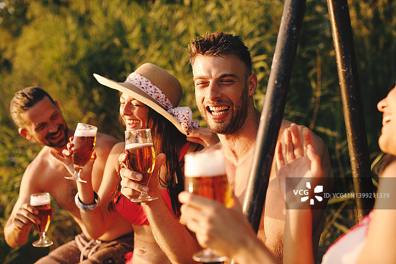 一群年轻人在夏日阳光明媚的日子里在河边喝啤酒图片素材