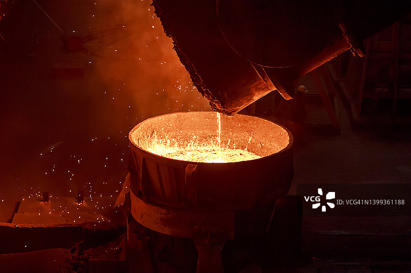 在炼铁厂，热钢从大铸钢包中注入模具。图片素材