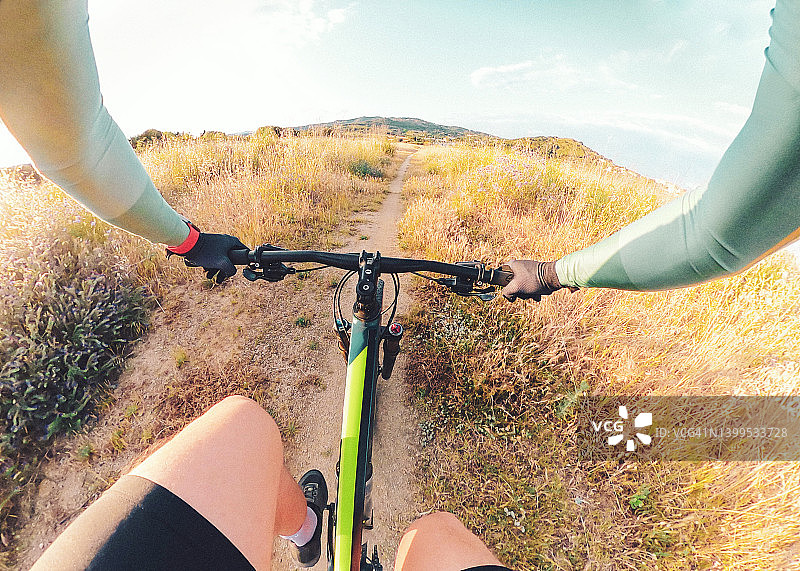 从个人角度出发，在草地之间的黄金时间骑山地自行车。图片素材