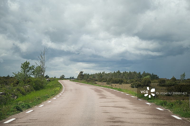 狭窄的乡村道路在春天的农业景观图片素材