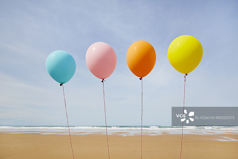 彩色气球在海滩上排成一排，映衬着天空图片素材