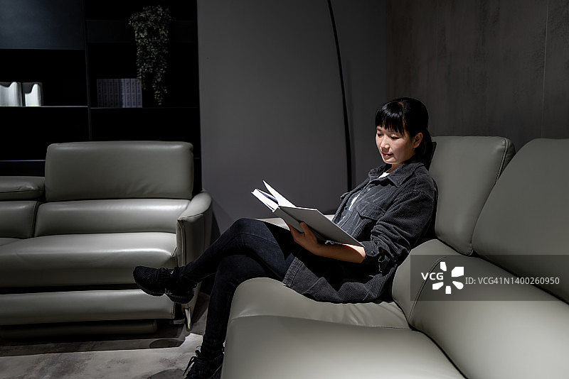 一个亚洲女人在沙发上看书图片素材