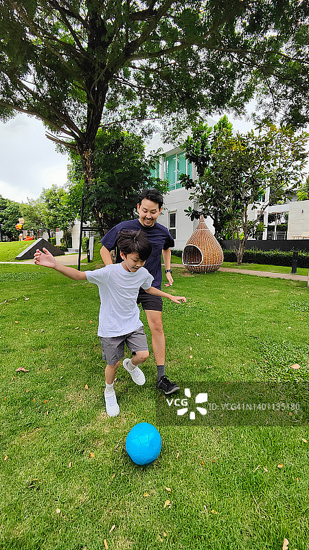 快乐的父亲和儿子在他们的后院踢足球图片素材