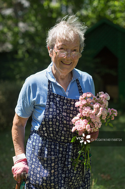 微笑成熟的女人在花园的花。特写镜头图片素材
