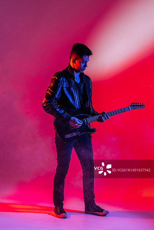 亚洲吉他手在霓虹灯下用吉他演奏音乐图片素材
