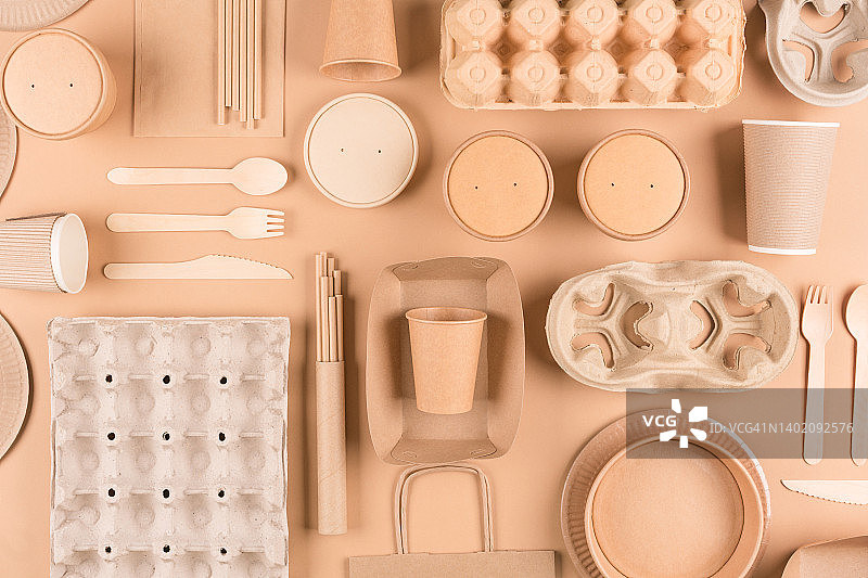 纸器皿和餐具，木制餐具，纸杯，盘子，袋子，纸浆鸡蛋盒和食品容器在浅棕色的背景。前视图。可持续食品包装理念图片素材