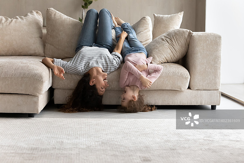 幸福的妈妈和小女儿倒着躺在沙发上图片素材