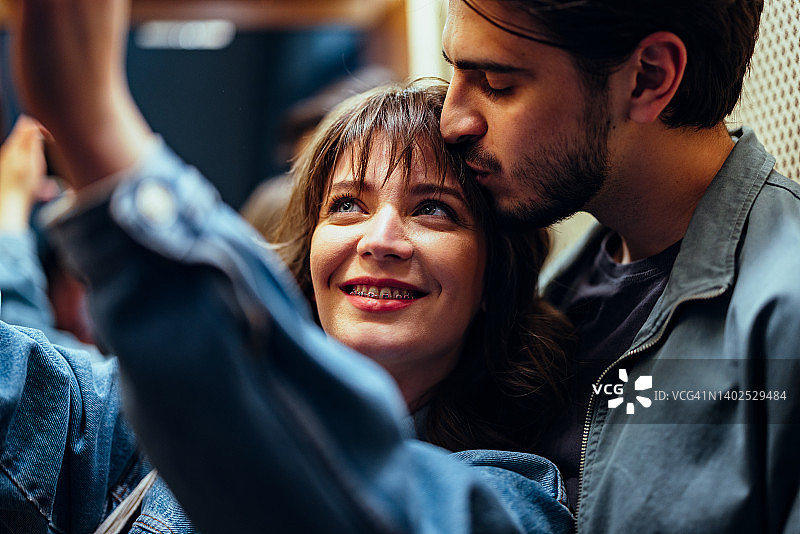 一对微笑的情侣在电梯里用手机自拍图片素材