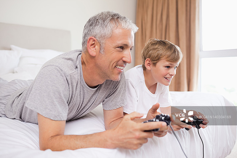 快乐的父亲和他的儿子玩电子游戏图片素材