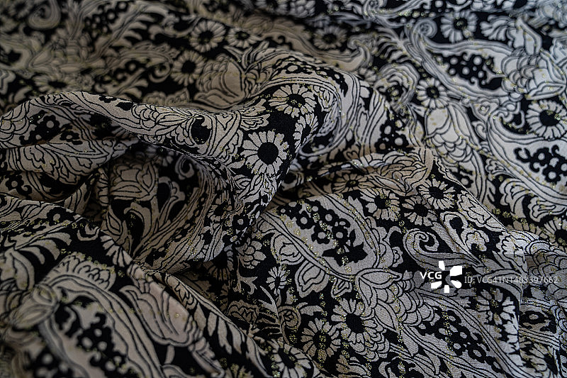 黑色织物与复杂的银光闪闪的设计。图片素材