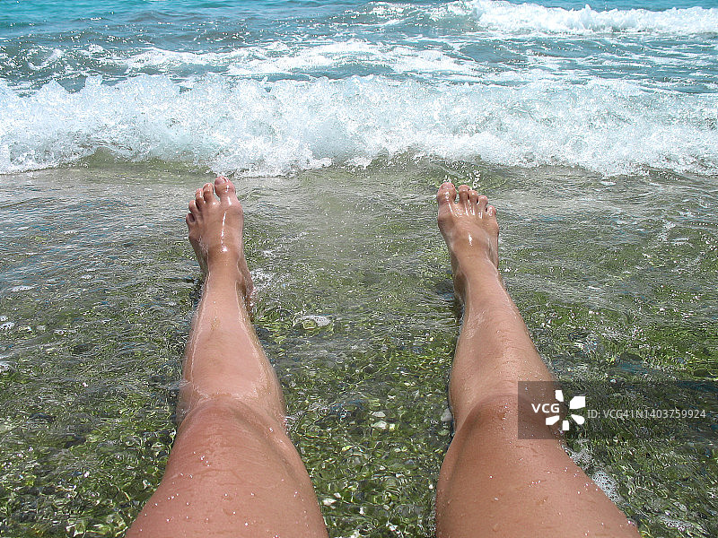 女性的双腿在海滩上海浪的背景图片素材